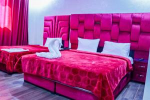 1 Schlafzimmer mit 2 Betten mit einem großen roten Kopfteil in der Unterkunft HOTEL BORJ EL ARAB in Khouribga