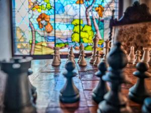 a chess board with chess pieces in front of a stained glass window at Hotel Castelo Nacional Inn Campos do Jordão in Campos do Jordão