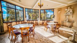 a dining room with a table and chairs and large windows at Hotel Castelo Nacional Inn Campos do Jordão in Campos do Jordão