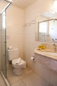 Un baño con inodoro, lavabo y espejo. en Pousada Águia Branca, en Gramado 56 fotos más