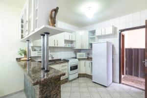 邦比尼亞斯的住宿－APARTAMENTO BEIRA MAR LATERAL NA PRAIA DE MARISCAL 2662，厨房配有白色橱柜和白色冰箱。