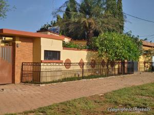 a fence in front of a house at Résidence des hibiscus-roses: jardin, piscine... in Ouagadougou