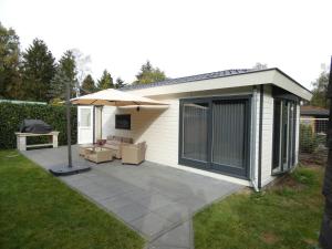 a backyard patio with an umbrella and a table at Veluwepark Reewold #Chalet Buizerd# tussen het bosrijke Putten en Garderen in Putten