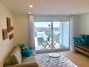 a living room with a couch and a sliding glass door at L'Azor Suites - Océan in Ponta Delgada