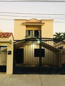 ein Gebäude mit einem Tor vor einem Haus in der Unterkunft “SCALLY CASA ENTERA”Los Mochis, la mejor ubicación in Los Mochis