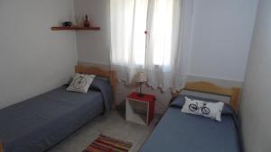 two beds in a small room with a window at Casa Las Calas in Puerto Madryn