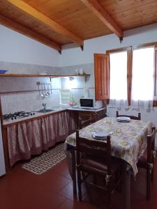 a kitchen with a table and a sink and a stove at Casa vacanza Ligustro appartamento il toro in SantʼAntìoco