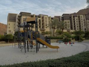 um parque infantil com um escorrega em frente a um edifício em Rental unit in RAHA village compound, special view em Aqaba