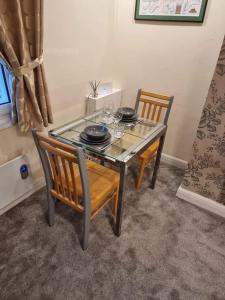 uma mesa de jantar com 2 cadeiras e uma mesa de vidro com óculos em Carlisle City Centre, Cute Victorian House. em Carlisle