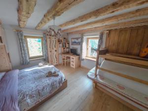 a bedroom with a bed and a desk and windows at Casa Soraya in Falcade