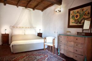 a bedroom with a bed and a chair and a dresser at Antico Borgo Sanda Lago Maggiore in Casalzuigno