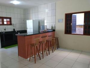 eine Küche mit einer Theke mit Hockern und einem Kühlschrank in der Unterkunft Casa Temporada Prainha de Mambucaba Paraty RJ in Paraty + 20 Fotos
