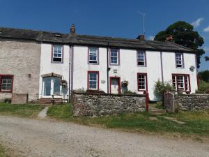 an old white house with a stone wall at Rainors farm cottage in Gosforth