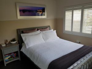 een slaapkamer met een bed met witte lakens en een raam bij Waterfront Location - 2 Bed Apartment in Corlette, Port Stephens - Sleeps 4 in Corlette
