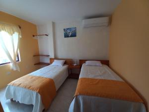 a room with two beds and a window at HOSTAL JANET STARLiNK in Puerto Villamil