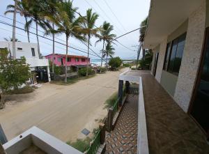 a balcony of a house with a street and palm trees at HOSTAL JANET STARLiNK in Puerto Villamil