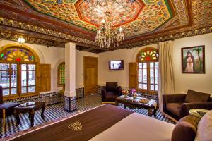 um quarto de hotel com uma cama e um lustre em Riad Marjana suites & Spa em Fez
