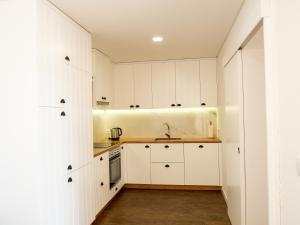 a kitchen with white cabinets and wooden floors at Casa da Portelinha in Arcos de Valdevez