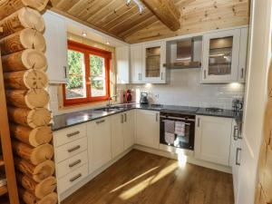 a kitchen with white cabinets and a wooden ceiling at Elm Lodge in Oakham