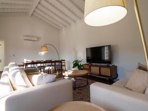 a living room with white furniture and a flat screen tv at Casa da Portelinha in Arcos de Valdevez