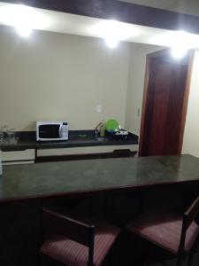 cocina con mesa con 2 sillas y microondas en Flat - Palladium Apart Service, en São Vicente