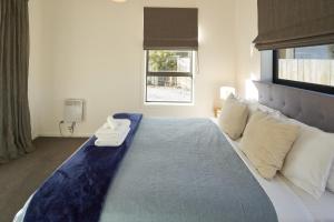 a bedroom with a large bed with a blue blanket at Kentmere Cottage in Lake Tekapo