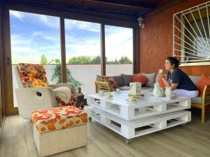 a woman sitting on a couch in a living room at LaCasitadelaPraderapuntoes in Torremocha de Jarama