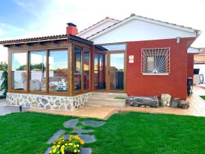 Torremocha de Jarama的住宿－LaCasitadelaPraderapuntoes，一座带大型玻璃窗和庭院的房子