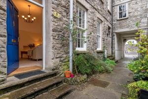 a stone house with a blue door and a pathway at Kent Cottage - Town centre, with parking in Kendal