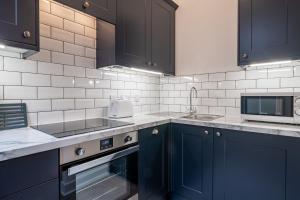 a kitchen with blue cabinets and a sink and a microwave at Kent Cottage - Town centre, with parking in Kendal