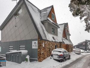 un bâtiment recouvert de neige avec une voiture garée devant dans l'établissement The Peak Penthouse 8, à Thredbo