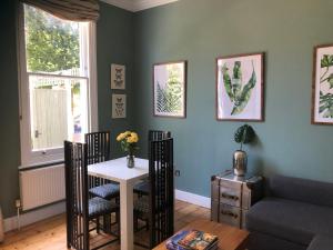 a living room with a table and chairs and a couch at By the Pagoda- cozy garden flat by Richmond & Kew Gardens in Kew Gardens