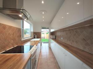 kuchnia z białymi szafkami i dużym oknem w obiekcie ChiPad Duo - Comfy house with garden & parking w mieście Chichester