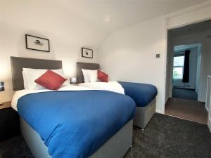 a bedroom with a large bed with blue sheets and red pillows at ChiPad Duo - Comfy house with garden & parking in Chichester