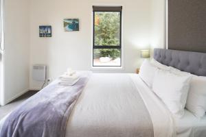 a bedroom with a large white bed with a window at Lily Cottage - Lake Tekapo in Lake Tekapo