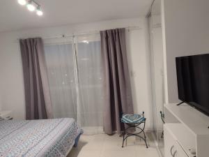 - une chambre avec un lit et une télévision à écran plat dans l'établissement Apartamento Costa del Sol, à Mar del Plata