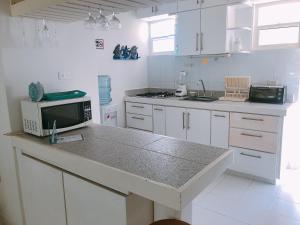 a kitchen with white cabinets and a counter with a microwave at Sitio exclusivo y tranquilo in San Andrés