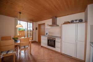 a kitchen with white cabinets and a table and a refrigerator at Utznhof in Seeon-Seebruck