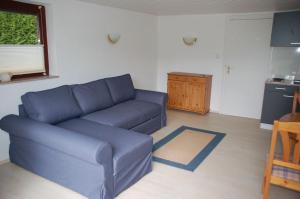 a living room with a blue couch and a kitchen at Haus Garten am Meer in Grömitz