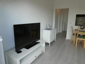 sala de estar con TV de pantalla plana en un centro de entretenimiento blanco en Strandkoje Watt'n Traum, en Büsum