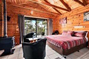 Dormitorio en cabaña de madera con cama y balcón en Lumera Eco Chalets, en Saint Marys