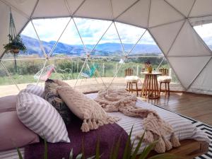 a bed in a tent with a view of a table at Amatea de Villa de Leyva in Villa de Leyva