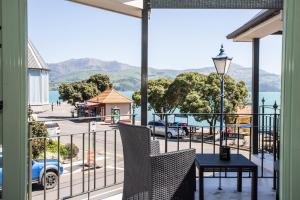 een balkon met een tafel en stoelen en uitzicht op een straat bij The Wharf Seaview Apartments by AVI in Akaroa