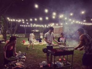 un grupo de personas de pie alrededor de una parrilla de barbacoa por la noche en Royal Garden Ba Vì Venuestay, en Ba Vì