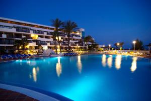 a large swimming pool in front of a hotel at night at Sandos Papagayo in Playa Blanca