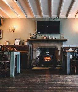 a living room with a fireplace with a television above it at Peak District, The Greyhound Inn, Warslow circa 1750 in Warslow