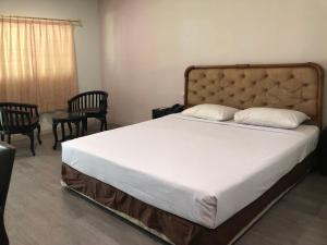 a bedroom with a large bed with two chairs and a window at Hotel Sinar 3 in Sedati