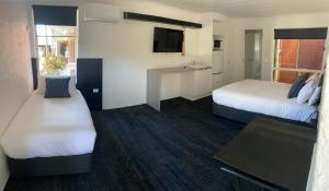 a hotel room with two beds and a television at Railway Motel Myrtleford in Myrtleford
