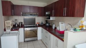 una cocina con electrodomésticos blancos y armarios marrones en Departamento Los Balcones en Cajamarca