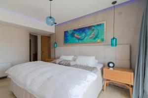 een slaapkamer met een wit bed en een schilderij aan de muur bij Candia Boulevard in Heraklion